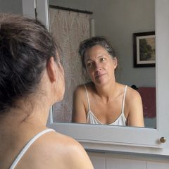Femme se regardant pensivement dans le miroir