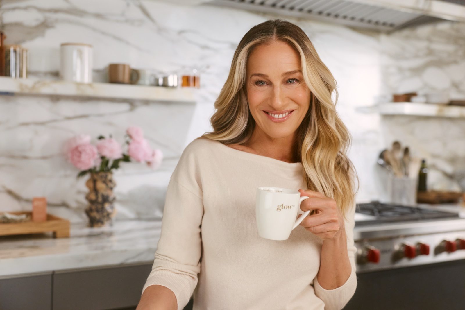 Sarah Jessica Parker, Chief Creative Officer chez Glow25, avec une tasse Glow25 dans sa cuisine